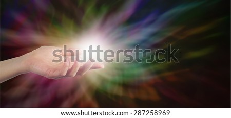 Energy Healer - Female Healer with hand out palm up with a ball of white energy appearing to manifest on a dark rainbow colored energy formation background banner with plenty of copy space