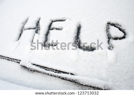 Help word written on front car window covered by heavy wet snow