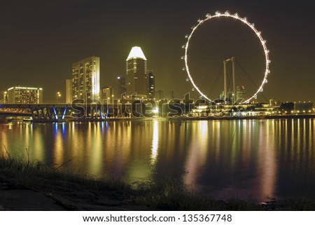 SINGAPORE - JANUARY 12, 2013: Singapore Flyer ferris wheel with scenic illumination as a part of night city skyline on January 12,  2013 in Singapore. It is the world\'s largest observation wheel.