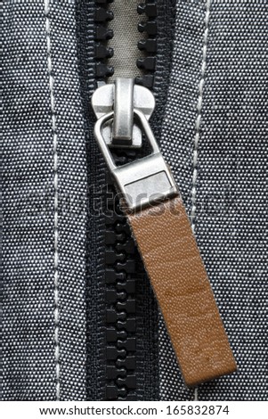 fragment of open plastic zipper fastener with brown leather tag