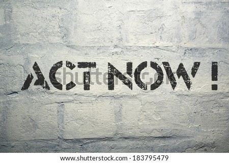 act now exclamation stencil print on the grunge white brick wall