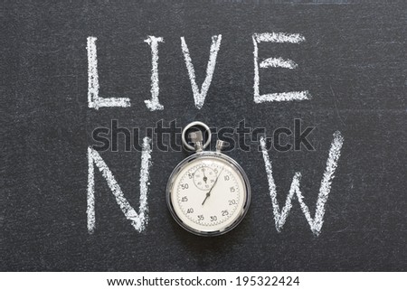 live now concept handwritten on chalkboard with vintage precise stopwatch used instead of O