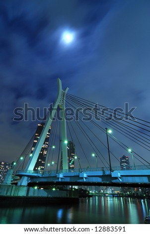 Chuo-Ohashi bridge in Tokyo, Japan by night with scattered moonlight behind moving clouds