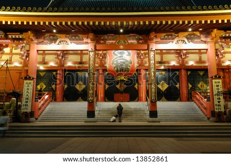 famous Tokyo landmark, Asakusa Temple colorful entrance by night with silhouettes of prayer woman and big dog, Tokyo, Japan