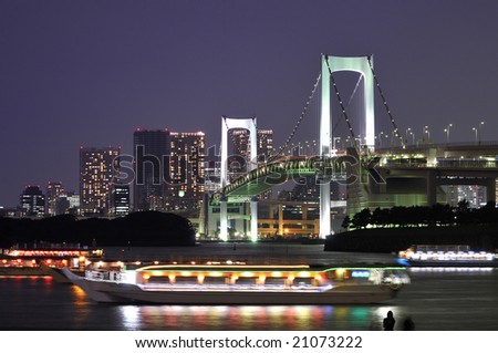 very famous Tokyo landmark, Tokyo Rainbow bridge over bay waters with scenic night illumination and traditional japanese boats