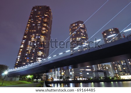 huge residential skyscrapers with illuminated windows beyond illuminated suspension bridge structure in Tokyo, Japan