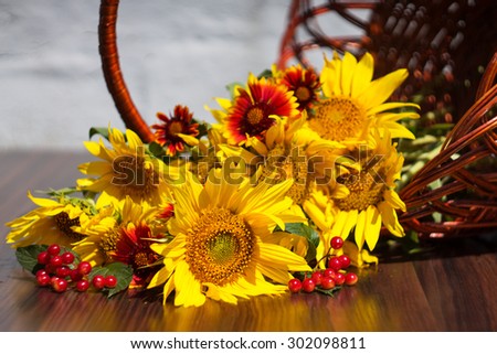 sunflowers with flowers and Viburnum lies in a basket on a blurred background