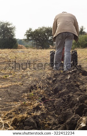 DIKANKA, UKRAINE - SEPTEMBER 30, 2015: Country farmer is plowing his garden with walk-behind garden tractor,autumn field work