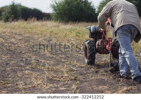 DIKANKA, UKRAINE - SEPTEMBER 30, 2015: Country farmer is plowing his garden with walk-behind garden tractor,autumn field work