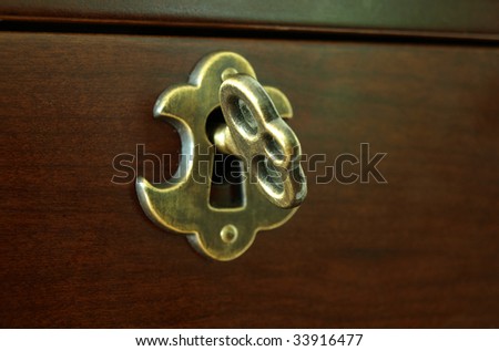 Old key opening a wooden drawer