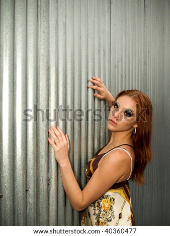 Attractive young woman with red hair posing in an industrial area
