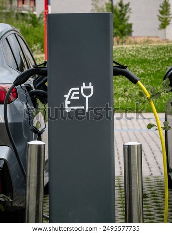 Foto Bild Mann schließt Elektroauto an Ladestation vor seinem Haus an