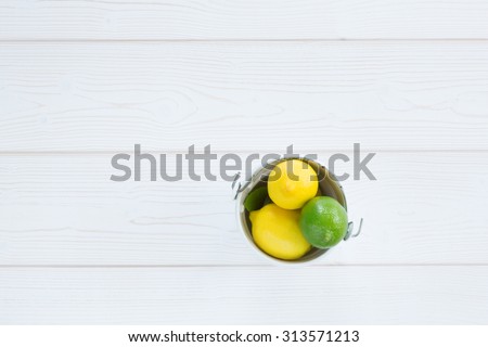 lemon yellow and lime green in a bucket on a white wooden background from above