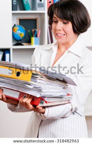 Portrait of successful business woman or teacher with folders at her office