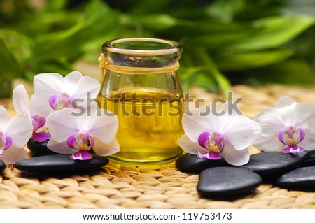 SPA background-candle with white orchid and stones ,massage oil with plant on mat
