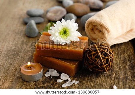 Pile of stones and flower with handmade soap, towel, candle on driftwood