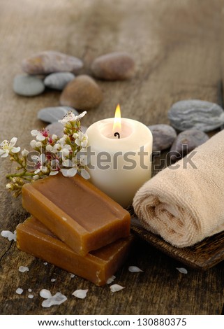Handmade soap, candle, soap ,stones, white flower petals on old wooden
