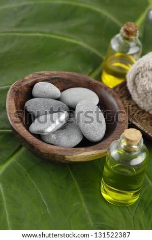 Roller towel in bowl and zen stones in bowl ,massage oil on green leaf