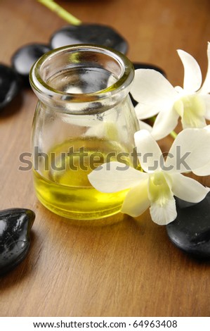 Massage oil and black stones with orchid in the spa