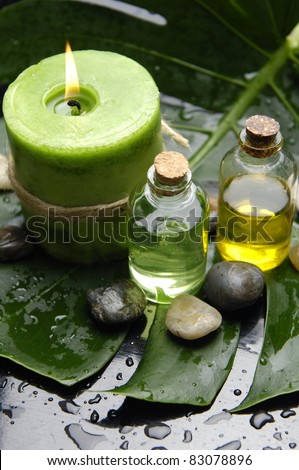 Green Spa-candle and massage oil with stones on leaf