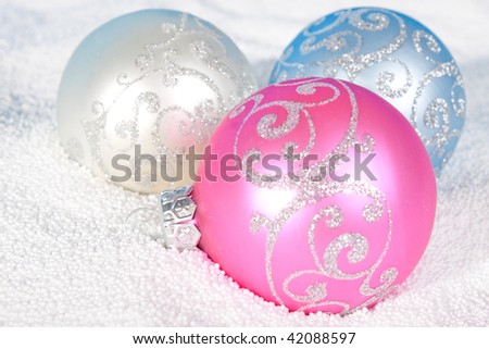 Tender Christmas bauble of rose, blue and white color on to snow.