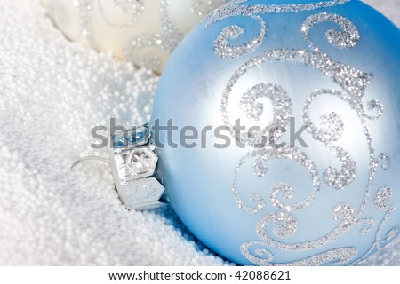 Tender blue Christmas bauble on white snow.