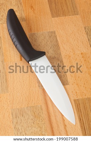 Ceramic knife with black handle on wooden cutting board