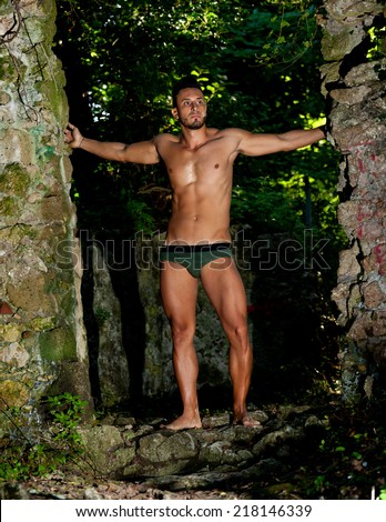 Handsome muscular man in briefs among the vegetation