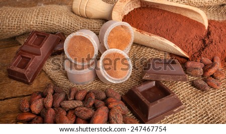 Capsules of chocolate with cocoa powder, cocoa beans and pieces of chocolate.