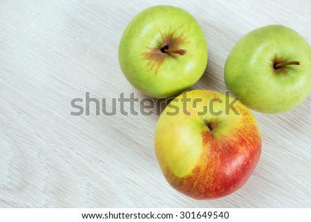 two green apples and red apple on a table, top view