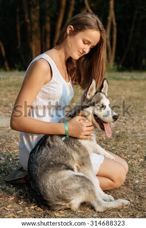 Young girl and her dog (husky) walking in autumn in a city park. Training the dog