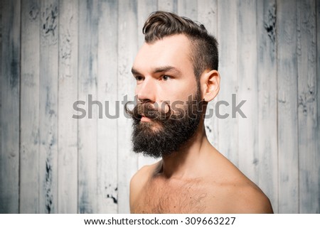 Portrait of bearded man with big mustaches. Shot on pale white painted wooden background.