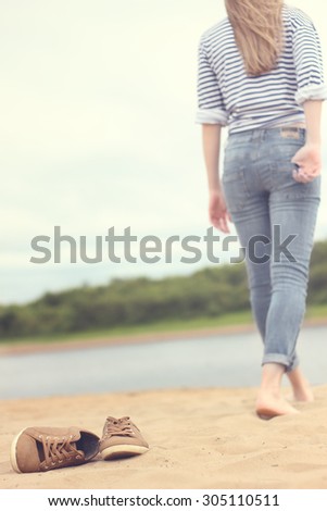 Girl walking on sand.I leave their shoes to feel the warmth of the sand