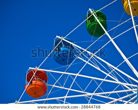 Fragment of wheel reviews with coloured cabins on background of blue sky