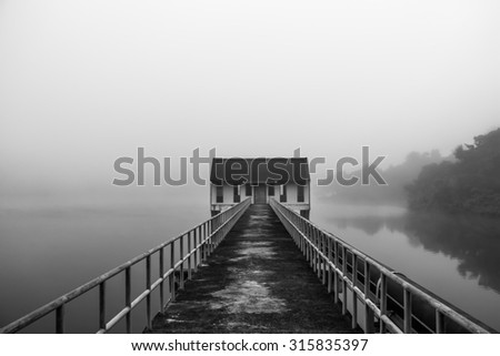 (Black and White) \
Bridge to station in the water, Amid heavy fog.