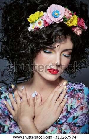 Fashion woman. Romantic girl with bright make-up, curly hair and a wreath of flowers. Colored arrows on eyes and red lips.