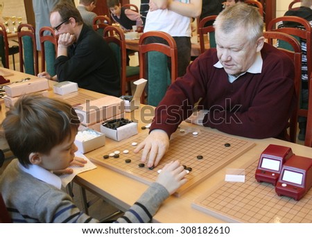 SAINT PETERSBURG, RUSSIA - Jan 29, 2012.  Chinese New Year Go Game Tournament. Valery Shikshin (go coach) is learning young boy to play go on the competition during the break.