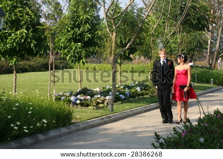 Young couple walking in a park dressed in formal wear.