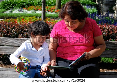 A Hispanic grandmother and grandson reading a book together