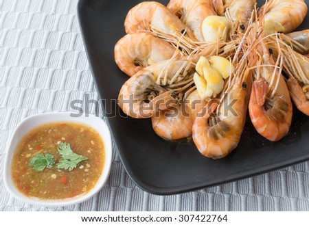 Thai cuisine , Baked shrimp with butter and garlic on a black plate, spicy sauce, placed on a gray tablecloth background.