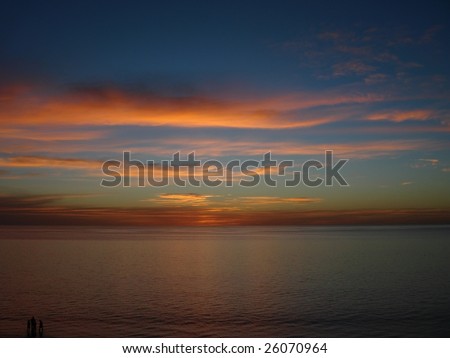 Small Family in Silhouette (lower left corner) against the full sky sunset.  Somerton Park Beach, Adelaide, Australia