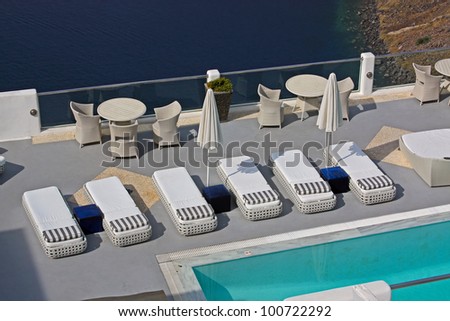 Row of pool chairs and umbrellas. Luxury hotel with caldera view at Santorini, Greece