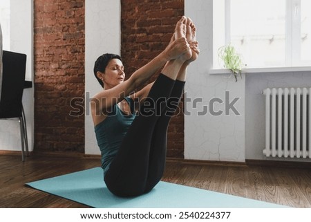 Similar – Image, Stock Photo Slim barefoot woman meditating in bound angle pose in contemporary workout room