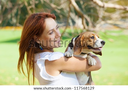 Girl playing with her beagle dog in autumn park