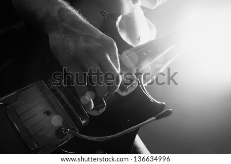 man playing electrical guitar in black and white