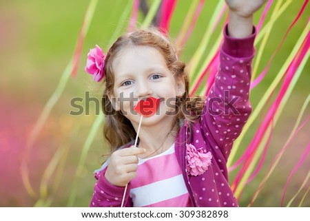 little girl holding paper lips on a stick