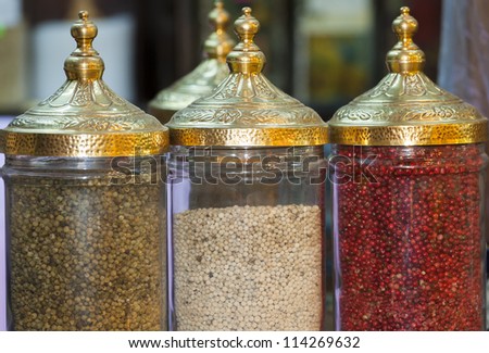 Display of peppercorns in ornate jars at an indoor market stall