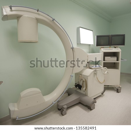 Large CAT scanner in a hospital operating room with monitor and lightbox