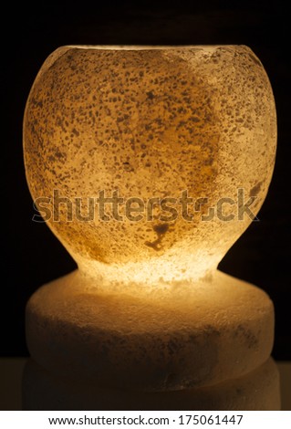 Ornate rock salt lamp and holder isolated on a black background