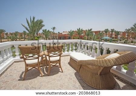 Wooden wicker chairs and sunbed on luxury tropical hotel balcony